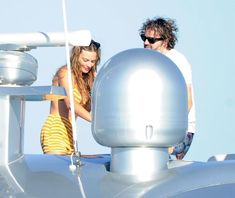 a man and woman standing on top of a boat