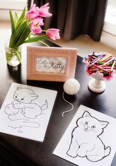 a table topped with paper cut outs and crayons next to a vase filled with flowers