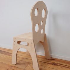 a wooden chair sitting on top of a hard wood floor next to a white wall