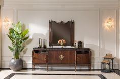 a large mirror sitting on top of a wooden cabinet next to a potted plant