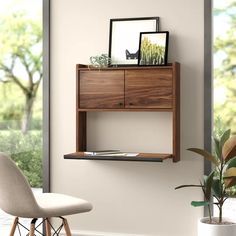 a wooden shelf with pictures on it next to a chair and potted plant in front of a window