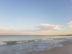 the ocean waves are rolling in and out of the water at sunset or dawn on an empty beach