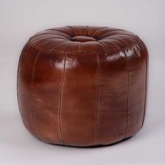 a brown leather poufce sitting on top of a white floor