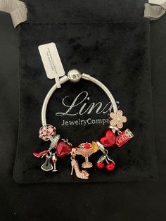 a charm bracelet with charms on it sitting in a velvet bag that says lin's jewelry company