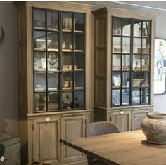 a wooden table sitting in front of a china cabinet with glass doors on it's sides