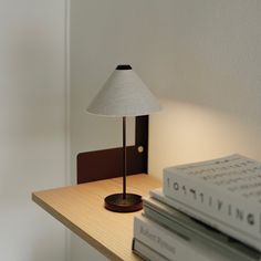 a lamp sitting on top of a wooden table next to books and a book case