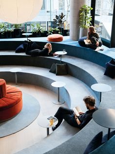 two people are sitting in the middle of a circular room with tables and couches