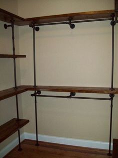 an empty room with wooden shelves and metal pipe shelving units on the wall, along with hardwood flooring