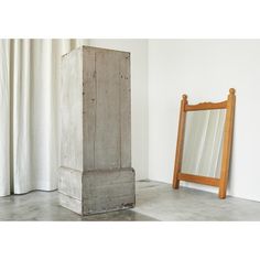 a wooden mirror sitting on top of a floor next to a tall piece of wood