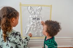 two children are playing with an easter bunny craft on the wall in their room at home