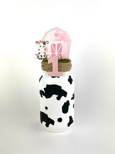 a white and black cow print jar with a pink number one on it