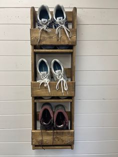 three pairs of shoes are sitting on a wooden shelf that is attached to the wall