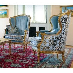 an ornately decorated living room with blue chairs and rugs on the floor in front of a window