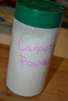 a white plastic cup with a green lid and pink writing on the side that says carpet powder