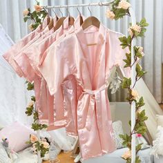 pink robes hanging on a clothes rack in a room with flowers and other things around