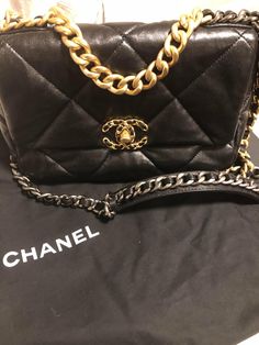 This is an authentic CHANEL Lambskin Quilted Medium Chanel 19 Flap in Black. This pillowy soft shoulder bag is crafted of oversized quilted goatskin leather in black. The refined bag features a chain detail CC turn-lock on the flap, a magnetic snap pocket on the back, a chunky matte gold chain top handle, and a leather threaded gradient gold to ruthenium chain-link shoulder strap. The front flap opens to a red fabric interior with a pocket. THIS ITEM IS FINAL SALE! Size Base length: 9.5 in Heigh Luxury Quilted Flap Bag, Designer Black Quilted Flap Bag, Designer Quilted Black Flap Bag, High-end Black Quilted Bag, Black Quilted Shoulder Bag For Everyday Luxury, Black Quilted Leather Flap Bag, Luxury Quilted Flap Bag With Top Handle, Luxury Quilted Top Handle Flap Bag, Black Quilted Flap Bag For Evening