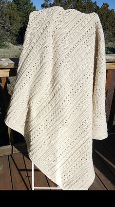 a white crocheted blanket sitting on top of a wooden deck