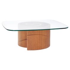 an oval glass and wood coffee table with circular wooden base in the center, against a white background