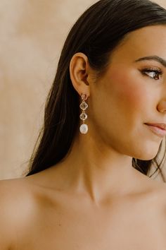 a woman in a strapless dress with earrings on her head looking off to the side