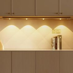 some books are sitting on a shelf in a room with beige cupboards and lights