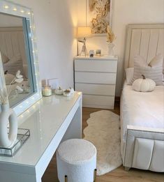 a bedroom with white furniture and lights on the walls, along with a large mirror