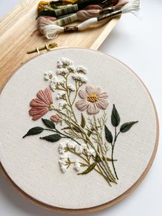 a close up of a embroidery on a wooden hoop with some flowers in the middle