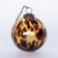 a glass ornament hanging from a rope on a white background with an animal print pattern