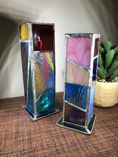 two stained glass vases sitting on top of a table next to a succulent plant