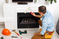 a man sitting on the floor in front of a fire place with tools around him