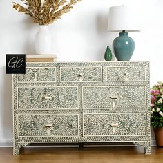 a green and white dresser sitting on top of a wooden floor next to a lamp