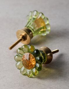 two green and yellow glass knobs sitting on top of a white counter next to each other