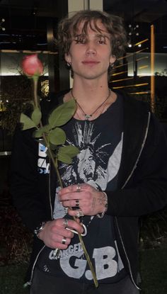 a young man holding a rose in his hands