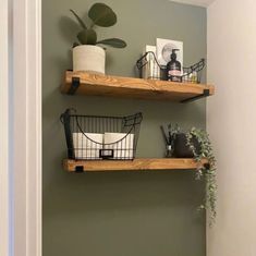 two wooden shelves with wire baskets on them in a small bathroom, one is green and the other is white