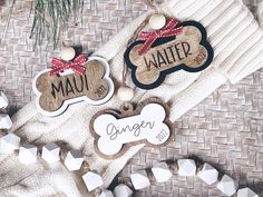 two personalized dog tags are sitting next to a christmas ornament on a wicker surface