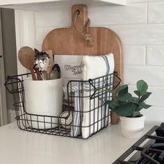 kitchen utensils and towels in baskets on the counter next to an oven hood