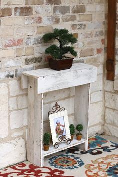 a small table with a potted plant on top and an empty shelf below it