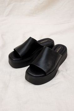 Vagabond Shoemakers Courtney platform slides. It is all about the characteristic flared outsole that makes this pool slide style the ultimate sandal of the season. The simple slip-on upper, made from black leather, is grounded by tonal flatform soles measuring 50 mm. Details include padded insoles and square toes. Heel height 50mm. Cow leather upper, Pu outsole, textile lining, cow leather inner sole. This style is made by Gia Ding Shoes Co. Ho Chi Minh City, Vietnam. 5134-001-92 / 5334-601-92 P Platform Black Slides, Black Leather Platform Sandals, Vagabond Courtney Sandals, Black Platform Slides Outfit, Black Slides Outfit, Platform Slides Outfit, Flatforms Sandals, Black Sandals Platform, Vagabond Sandals