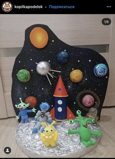 there is a cake that looks like an outer space scene with aliens and planets on it