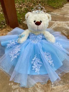 a white teddy bear wearing a blue dress