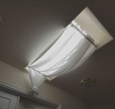 the light shines through the white drapes on the window in the room with the closet door open