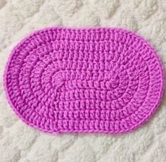 a pink crocheted dishcloth laying on a white surface next to a pair of scissors