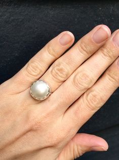 Choose your color and your ring size! This elegant and stately pearl ring is made from a beautiful and unique white cream 14mm Mabe South Sea AAA Pearl that has many hues including pink. The pearl has been set in sterling silver with a sterling silver ring band handmade from half dome wire. This ring has some height, the setting is almost 1/2 inch high. The white cream pearl is more matte than the other mabe pearls listed, but still has a luminescent quality that makes it captivating!Made to ord Classic White Pearl Ring With Pearl Charm, Classic White Pearl Ring With Charm, Classic White Pearl Ring With Drop Detail, Elegant White Pearl Ring With Charm, Classic White Pearl Ring, Elegant White Pearl Ring Gift, White Pearl Drop Ring For Anniversary, White Pearl Drop Ring, Wedding Pearl Ring With Bezel Setting