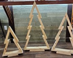 three wooden christmas trees sitting next to each other on top of a hard wood floor