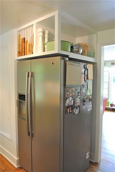 a silver refrigerator freezer sitting inside of a kitchen next to a wooden floor and white walls