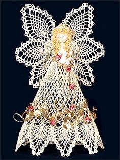 a crocheted angel with roses on it's chest and wings, standing in front of a black background