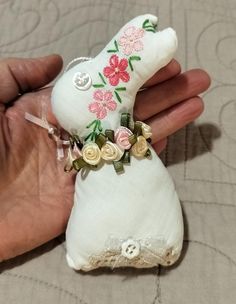 a hand holding a small stuffed animal with flowers on it