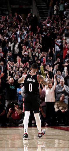 two basketball players in the middle of a court with their hands up and fans behind them