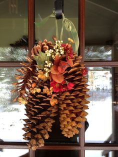 a wreath made out of pine cones and flowers