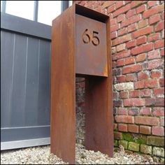 a metal mailbox sitting in front of a brick building with the number 55 on it