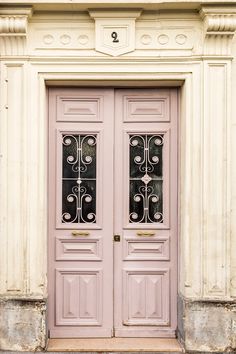 two pink doors with wrought iron bars on the front of an old building in europe